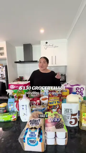 A woman standing at her kitchen bench beside a grocery haul