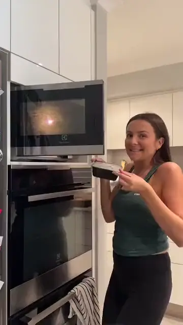 A woman eating a bowl of food and giving an OK sign