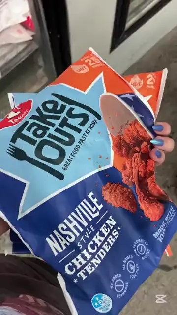 A hand holding up a pack of smoked salmon beside a shopping trolley